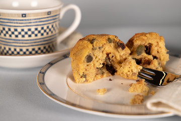 Banana chocolate chip muffin on side plate, light blue background, with shallow depth of field.