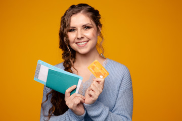 Happy smiling woman holding passport with tickets and orange credit card, exited person with credit card and passport with tickets