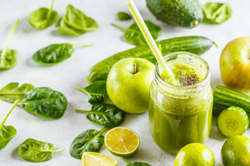 Naklejka na ściany i meble Green healthy smoothie (juice) in the jar. Apple, spinach, cucumber smoothie on white background with the ingredients.