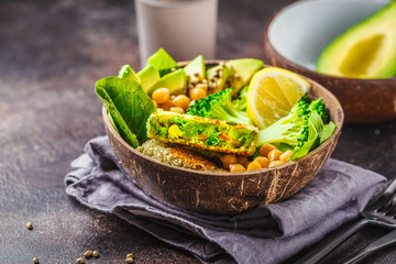 Vegan lunch in a coconut bowl: green burgers with salad and chickpeas.
