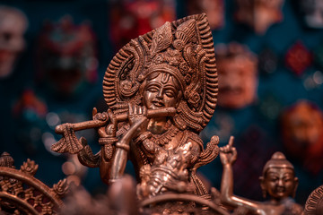 Golden and brass religious indian statues. Close up and details of traditional artisan objects, asiatic culture concept. Soft light, blurred background, macro shot.  