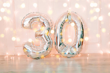 Silver foil birthday balloons number 30 with glitter lights.