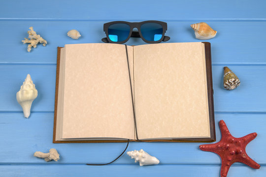 Blue wooden background with seashells, open empty page of notebook and sunglasses 