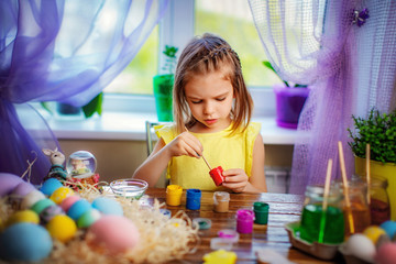 colorful painted eggs, flowers in vase. Happy easter girl having fun and painting eggs. small child at home. spring holiday