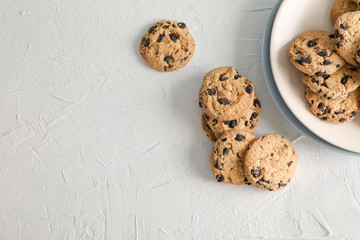 Plate with tasty chocolate chip cookies  on gray background, top view. Space for text
