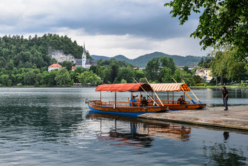 Beautiful Lake Bled in the Julian Alps and two old wooden boats. Mountains, clear aquamarine water,...