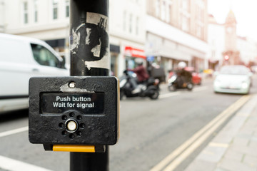Close up of yellow metal crosswalk button for pedestrian crossing signal in London, UK for traffic...