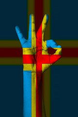 Hand making Ok sign, Aland islands flag painted as symbol of best quality, positivity and success - isolated on flag background