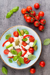 Delicious caprese salad with ripe cherry tomatoes and mini mozzarella cheese balls with fresh basil leaves.