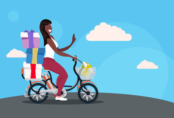 Fototapeta na wymiar woman cycling bicycle carrying wrapped presents gift boxes holiday celebration concept african american girl riding bike female cartoon character full length horizontal flat