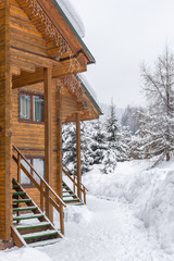 Chalet in the ski resort. Wooden house in the resort Bukovel in Ukraine. Two-storey cottages of logs. Natural building materials. Winter country landscape. Snow-covered houses. Wooden facade.