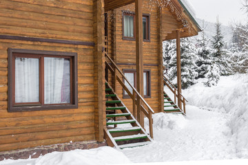 Chalet in the ski resort. Wooden house in the resort Bukovel in Ukraine. Two-storey cottages of logs. Natural building materials. Winter country landscape. Snow-covered houses. Wooden facade.