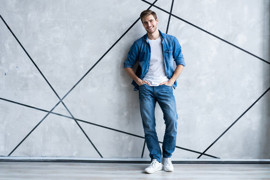Modern and casual. Full length of handsome young man in jeans shirt looking at camera with smile while standing.