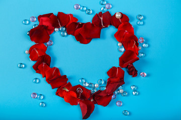 A heart lined with rose petals on a blue background in the design of white and pink beads.