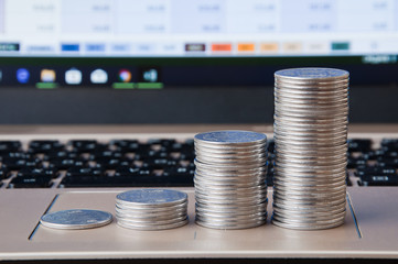Rising columns of coins near the keyboard on the background of the laptop's on-screen display