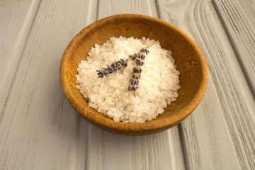 Sea bath salt and dried lavender in the brown bowl on the grey wooden background