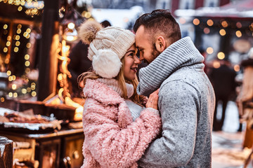 An attractive couple in love, a stylish couple wearing warm clothes cuddling together and looking...