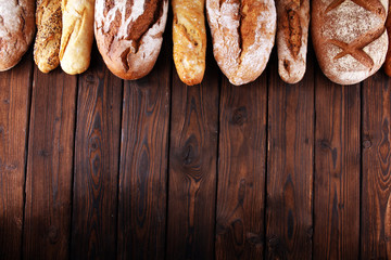 Assortment of baked bread and bread rolls on wooden table background