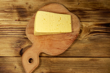 Piece of cheese on cutting board on wooden table