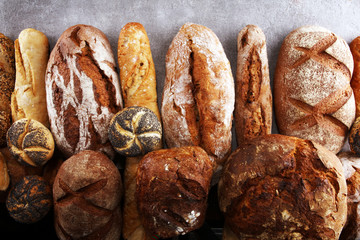 Assortment of baked bread and bread rolls on stone table background