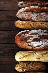Assortment of baked bread and bread rolls on wooden table background