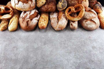 Assortment of baked bread and bread rolls on stone table background
