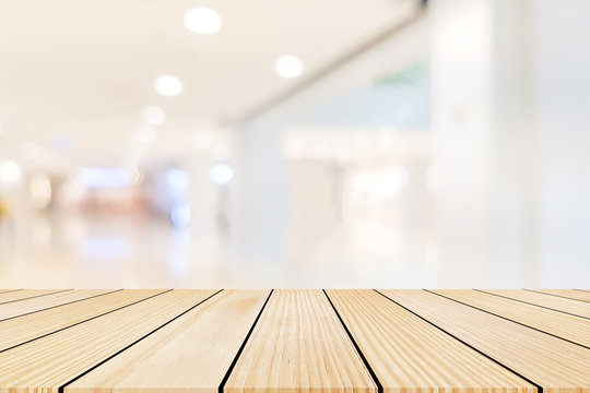 Blurred lamp light at shopping mall in white color background with old vintage grungy brown wood panel tabletop for show,promote and advertise product on display