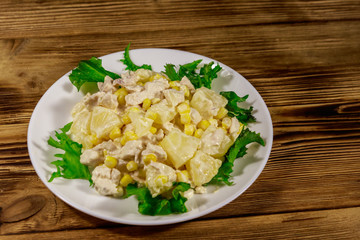 Festive salad with chicken breast, sweet corn, canned pineapple and mayonnaise on wooden table