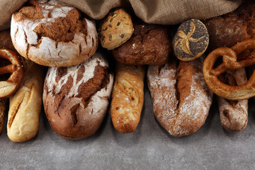 Assortment of baked bread and bread rolls on stone table background