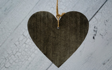 Big dark wooden heart on the white wooden background. Close up and big copyspace for your text