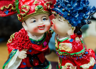 Cute ceramic figure with Chinese's traditional wedding costume clothes or dress. Concept of old fashion Asian bride and groom. Slightly defocused and close-up shot. 