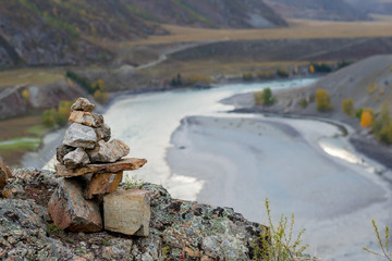 Stones stacked slide on top of each other in a tourist picturesque mountain range in the valley with the turquoise river, autumn