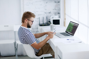 business man sitting at desk in office and looking at open laptop workstation.