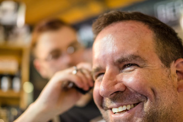 Happy guy getting haircut by hairdresser