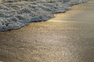 Close up shot of waves breaking on the sandy beach at sunrise
