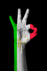 Hand making Ok sign, Tajikistan flag painted as symbol of best quality, positivity and success - isolated on black background