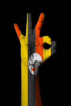 Hand making Ok sign, Uganda flag painted as symbol of best quality, positivity and success - isolated on black background
