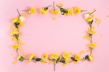 Frame of yellow flowers on a pink background. Top view with copy space.