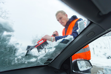 Man cleaning car windshield from snow and ice