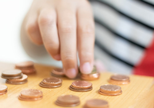 Child Hand Staking The Coins On The Table