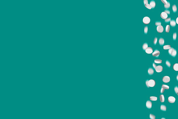 Falling medical pills on green background