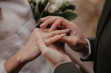 Obraz na płótnie Canvas Groom wears golden wedding ring on the bride finger. Wedding ceremony