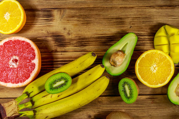 Assortment of tropical fruits on wooden table. Still life with bananas, mango, oranges, avocado, grapefruit and kiwi fruits