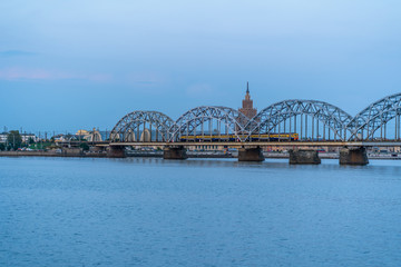 View of Cityscape with Railway Bridge and Train on it in Riga, Latvia, on Blue Hour, Twilight with a Free Space for Text, Concept of Travels