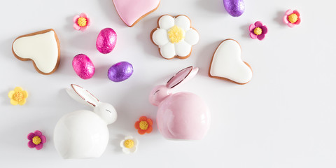 Easter eggs, cookies, sweets, porcelain rabbit, easter decorations on white background. Minimum Easter holiday concept. Flat lay, top view, copy space