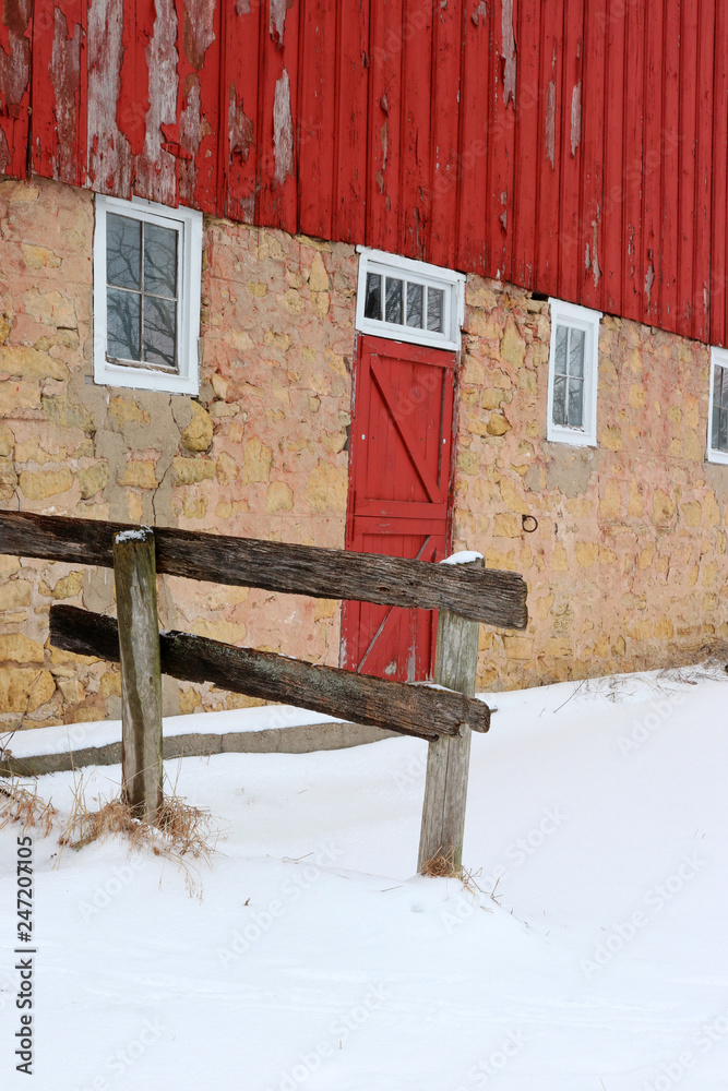 Wall mural snowy winter view with old red barn. old style stoned red barn and yard covered by snow close up. wi