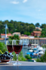 Two wine glasses with red wine served with red grape on outdoor terrace