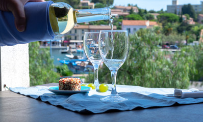 Waiter pouring white wine on outdoor cafe terrace