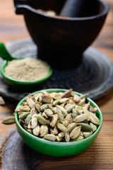 Bowl with cardamom pots and cardamom powder, used for cooking and traditional medicine close up, spices collection