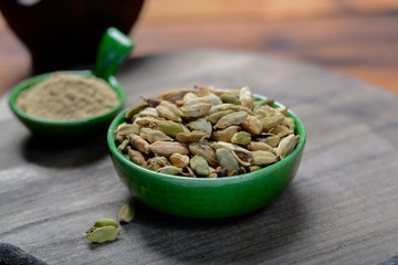 Bowl with cardamom pots and cardamom powder, used for cooking and traditional medicine close up, spices collection